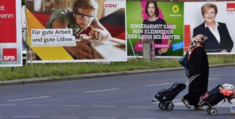 A woman wearing a hijab passes by several election banners for the September general elections in Berlin, on August 23, 2017.  Photo: AFP