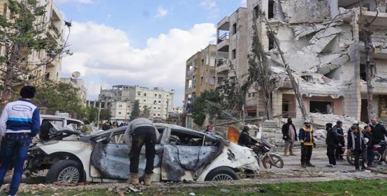 The wreckage of a car and a damaged building in the background are seen in Syria's militant-held city of Idlib on February 18, 2019, following a double bomb att
