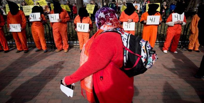 A woman walks past activists protesting the Guantanamo Bay detention camp during a rally in Lafayette Square outside the White House January 11, 2018 in Washing