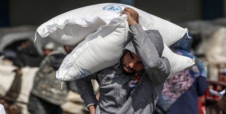 Palestinian man carries on his shoulder sacks of flour received from UNRWA in Gaza Strip.  (Photo: AFP)