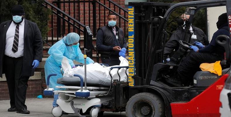 Workers prepare to load a deceased person into a trailer outside of Brooklyn Hospital Center in New York City.  (Photo: Brendan Mcdermid/Reuters)